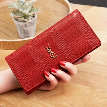 Billetera larga roja con diseño cuadriculado sostenida en la mano