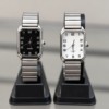Reloj analógico rectangular plateado con esfera negra y vista de malla