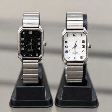 Reloj analógico rectangular plateado con esfera negra y vista de malla