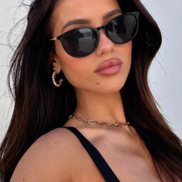 Mujer con anteojos de sol ovalados negros y patillas doradas